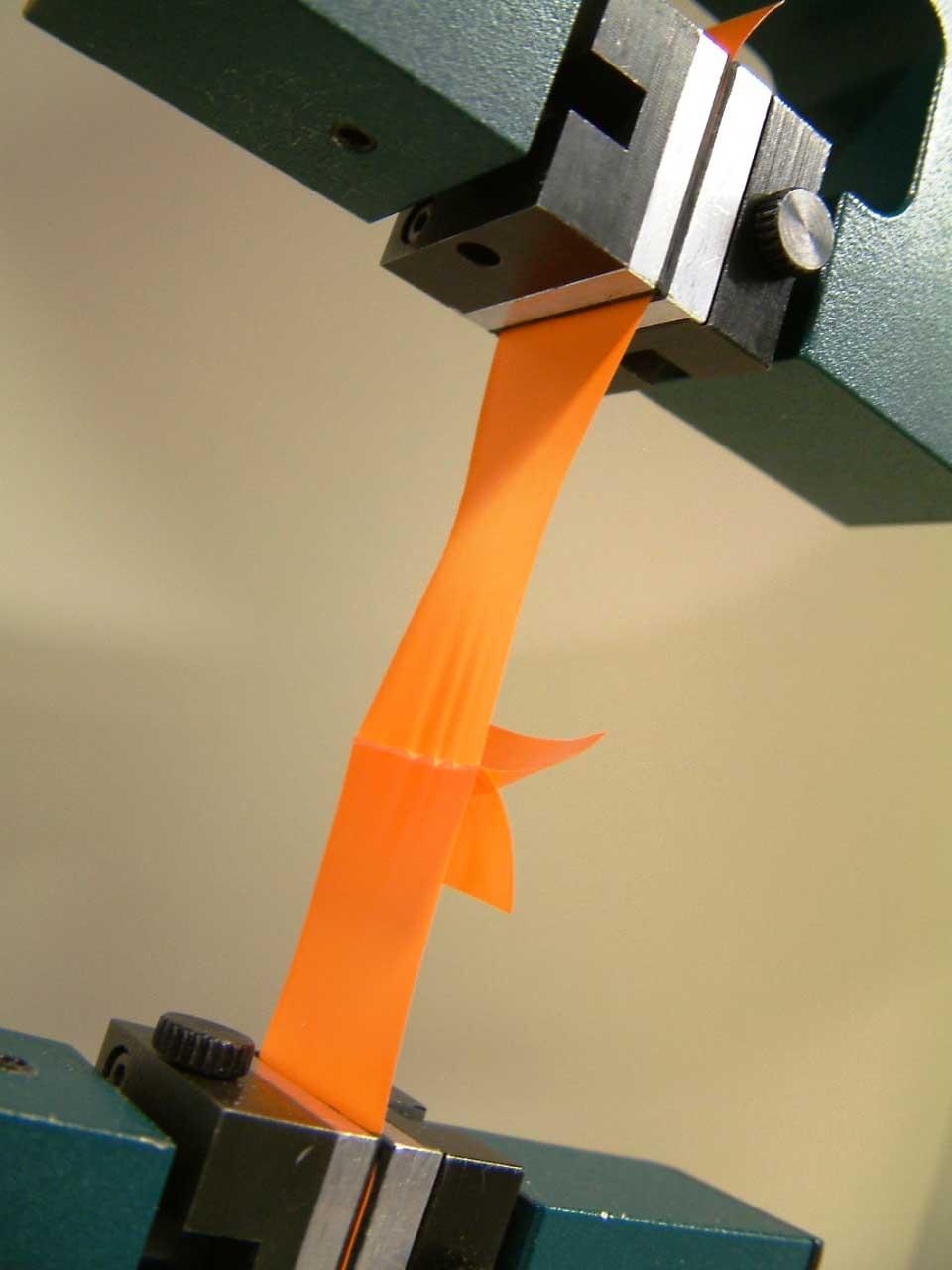 A close up view of plastic tensile testing, where plastic is effectively being stretched in different directions.
